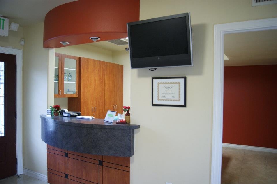 The reception counter, curving under an orange soffit, with wood cabinets behind it